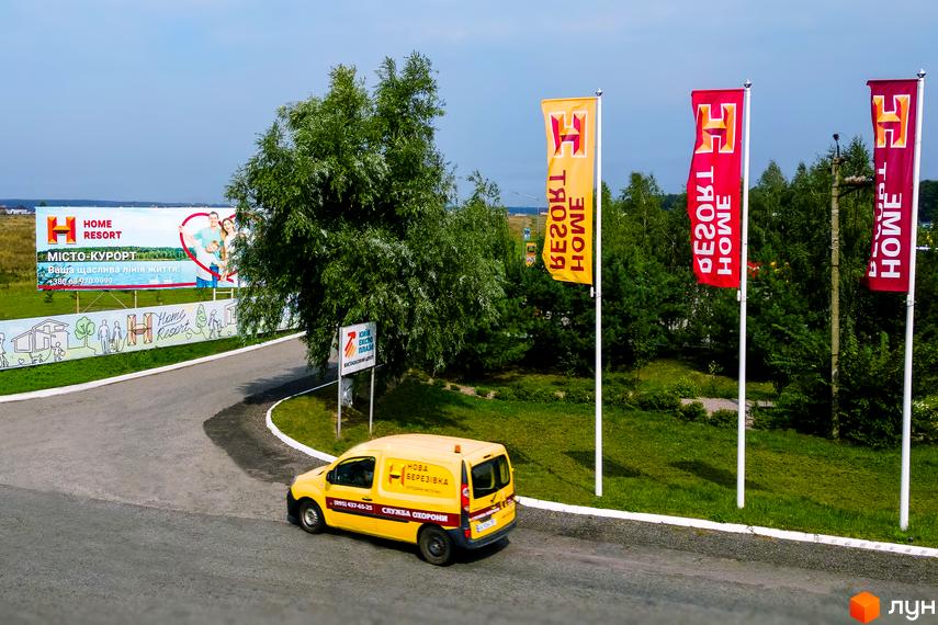 Котеджне містечко Home Resort: зовнішній вигляд комплексу та прибудинкова територія з прапорами та автомобілем.