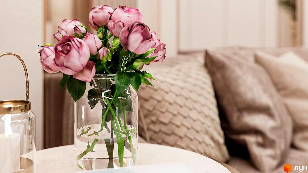 Клубний будинок LA MANCHE. Букет рожевих троянд у скляній вазі на столику. На задньому плані диван з подушками.