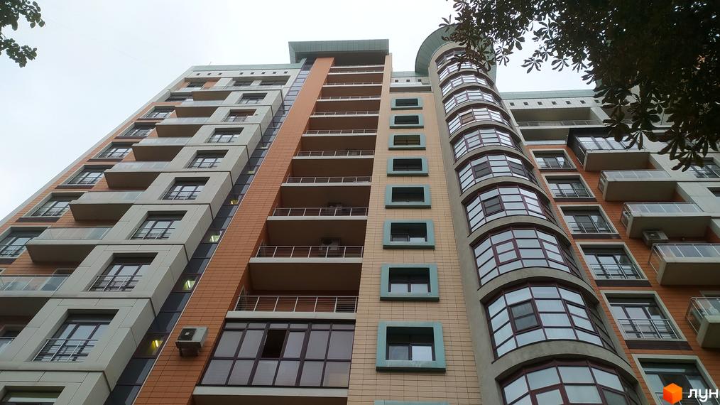 Зовнішній вигляд новобудови ЖК Капітолій з численними балконами та вікнами. Фасад будинку оздоблений цегляними та світлими елементами.