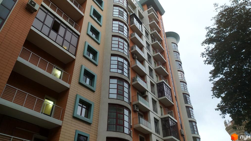 Зовнішній вигляд житлового комплексу Капітолій з балконами та великими вікнами. Будівля має цегляний фасад та сучасний дизайн.