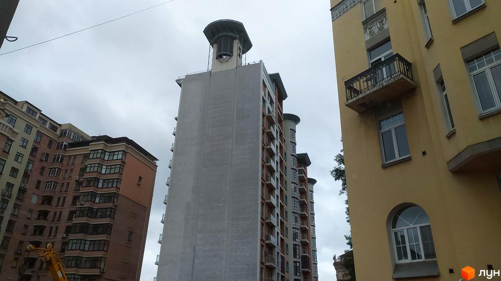 Житловий комплекс Капітолій: високі будинки з балконами та вікнами на тлі хмарного неба. Зовнішній вигляд новобудови з цегляним та сірим фасадом.