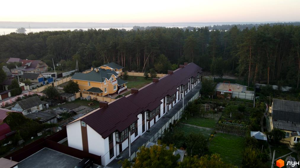 Таунхауси Green Heaven: двоповерхові будинки з коричневими дахами та білими стінами, оточені зеленою територією та деревами.