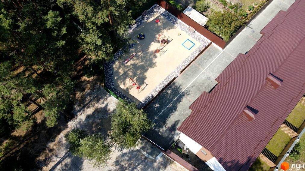 Таунхауси Green Heaven - цегляні будинки з коричневими дахами та дитячим майданчиком поруч. Навколо зелені дерева та пішохідні доріжки.