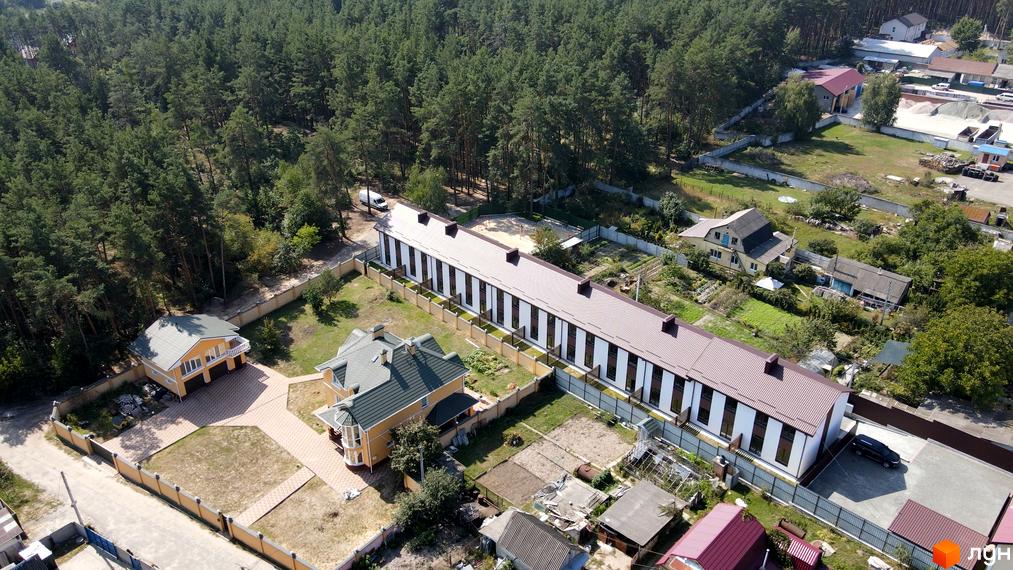 Таунхауси Green Heaven - це двоповерхові будинки з коричневим дахом та білими стінами, розташовані серед зелених насаджень з доглянутою прибудинковою територією.