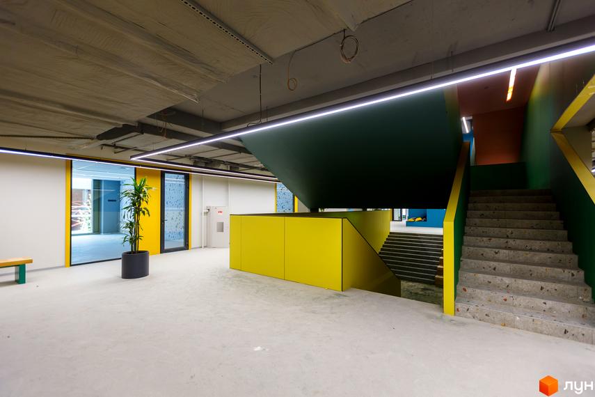 Сучасний інтер'єр житлового комплексу Rybalsky з яскравими жовтими та зеленими акцентами та сходами.