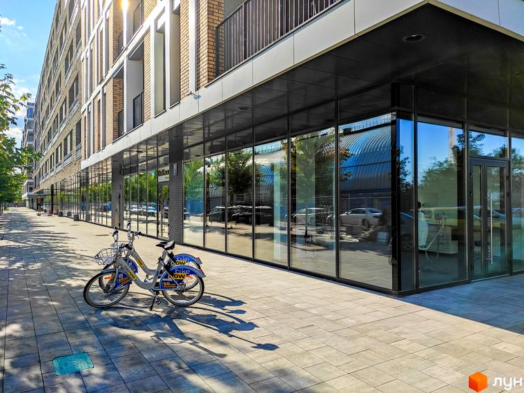 Житловий район Rybalsky. Сучасна архітектура з великими вікнами та балконами. Поруч розташована велопарковка та доглянутий тротуар.