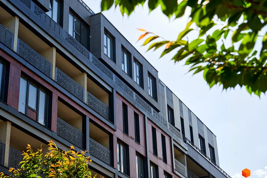 Фасад житлового району Rybalsky з балконами та вікнами. Сучасна архітектура новобудови з дерев'яними та темними елементами.