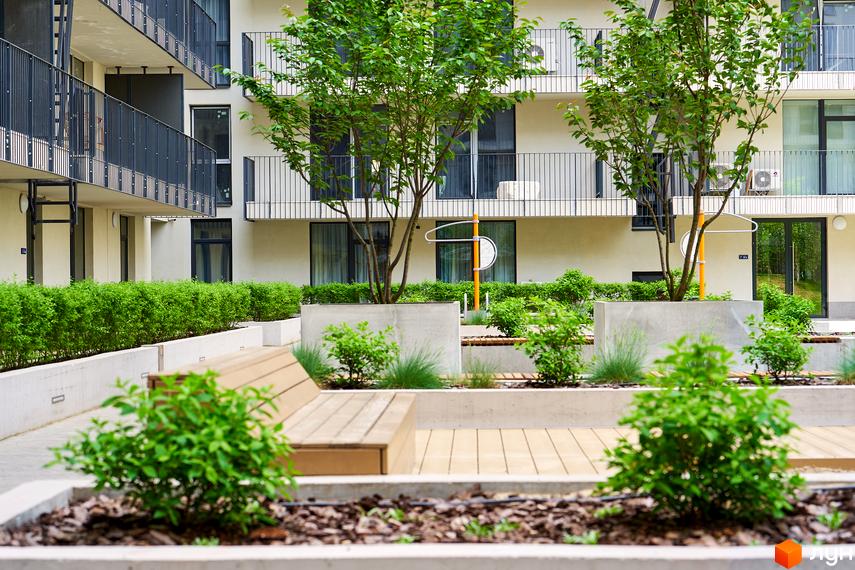 Житловий район Rybalsky: фасади будівель з балконами та зелені зони з лавками та деревами. Прибудинкова територія з ландшафтним дизайном.