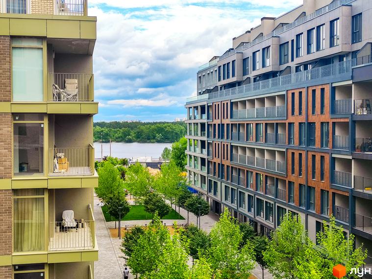 Житловий район Rybalsky. Сучасні багатоквартирні будинки з балконами та вікнами, що виходять на річку та зелену зону з деревами.