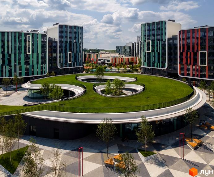 Житловий комплекс Respublika: багатоповерхові будинки з кольоровими вертикальними панелями. На території великий зелений дах та вимощена площа з лавками.