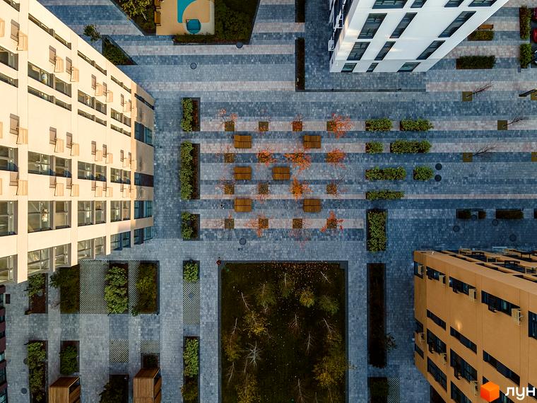 Аерофотознімок житлового комплексу Файна Таун з бежевими та білими будинками, мощеними доріжками, зеленими насадженнями та лавками.