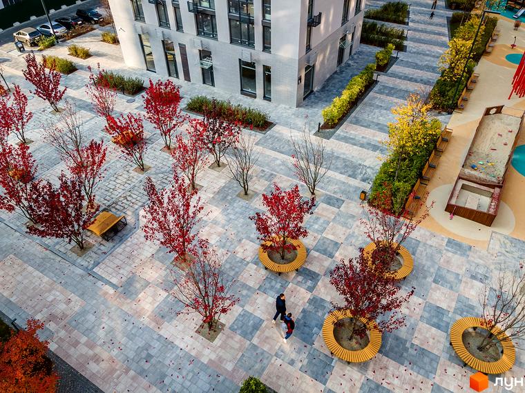 Світлий багатоповерховий будинок Житлового комплексу Файна Таун. Дворик з бруківкою, осінніми деревами, лавками та майданчиком.