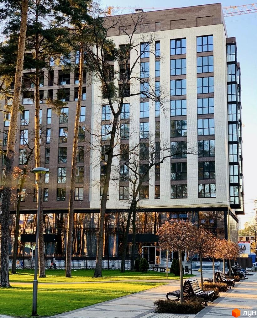 Будинок житлового комплексу Art Residence з цегляним фасадом та великими вікнами, оточений деревами та парковою зоною з лавками.