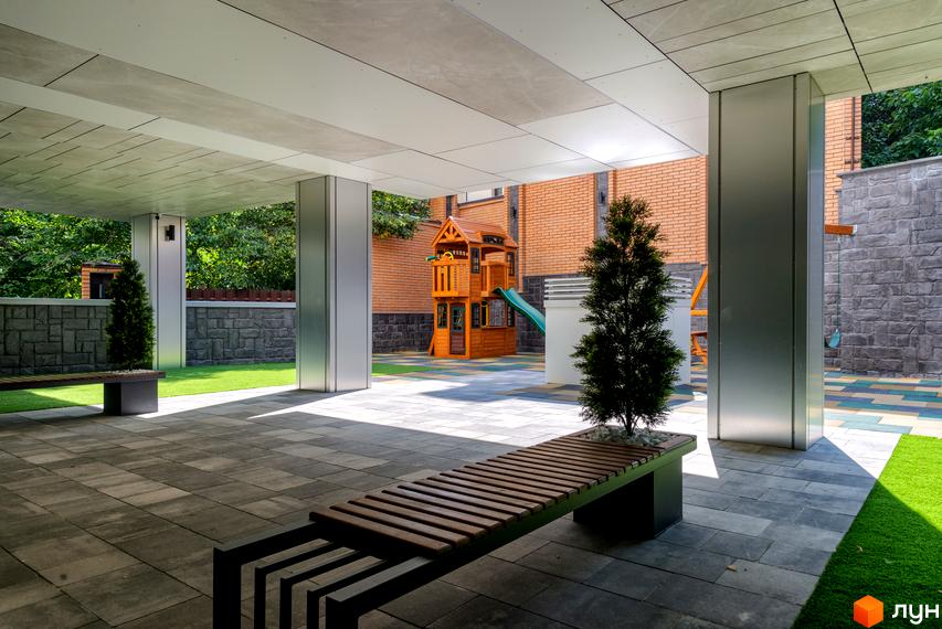 Приклад дизайну фасаду та прибудинкової території клубного будинку Hidden: відкритий простір, лави, зелені насадження та дитячий майданчик.