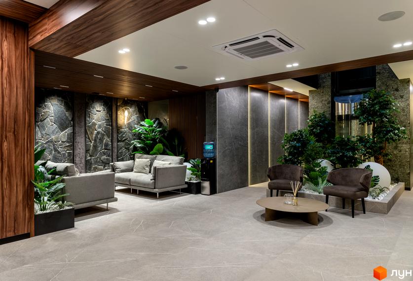 Інтер'єр холу в клубному будинку Hidden з диванами, кріслами, рослинами та декоративним освітленням. Просторий та світлий простір з елементами каменю та дерева.
