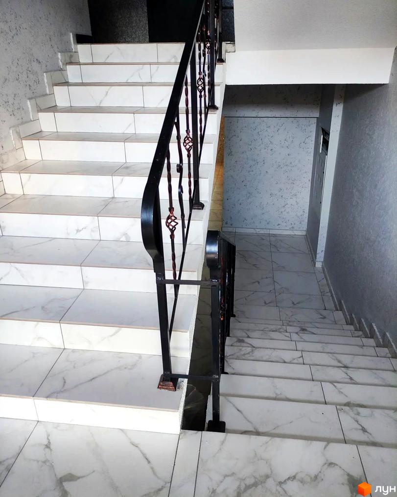 Сходи в новобудові ЖК Green Life-3 з мармуровим покриттям та кованими поручнями. Зовнішній вигляд сходів та внутрішнє оздоблення приміщення.