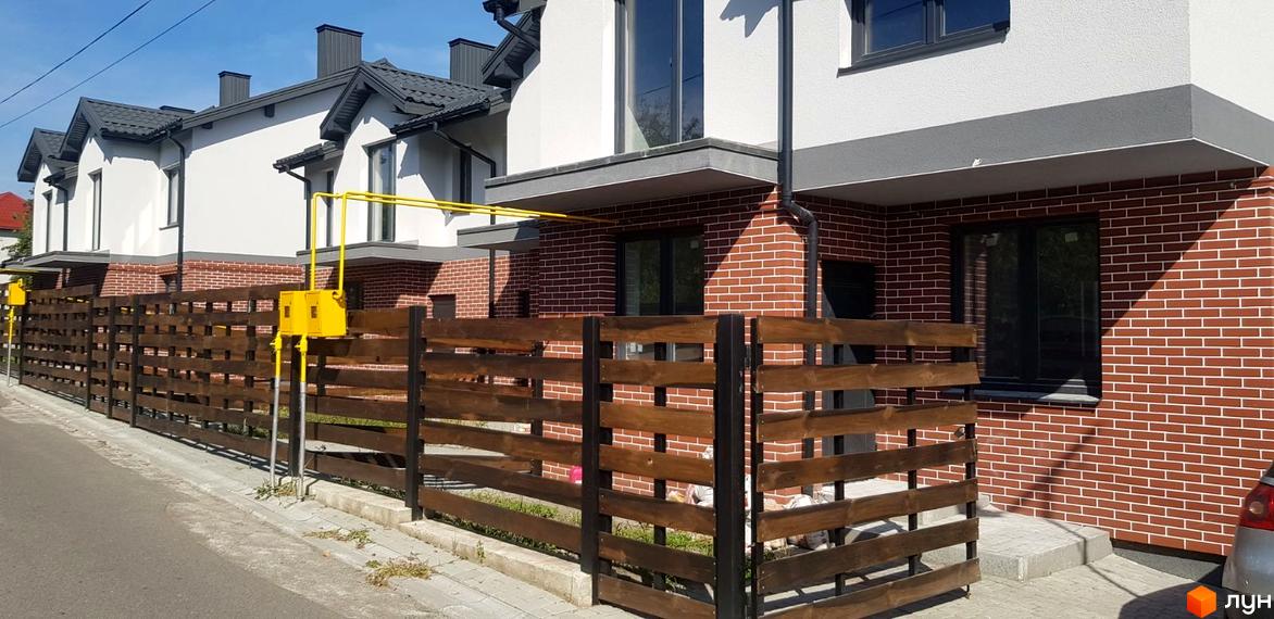 Котеджне містечко КМ Скандинавія. Зовнішній вигляд будинків з червоної цегли та білої штукатурки, дерев'яний паркан та газові труби.