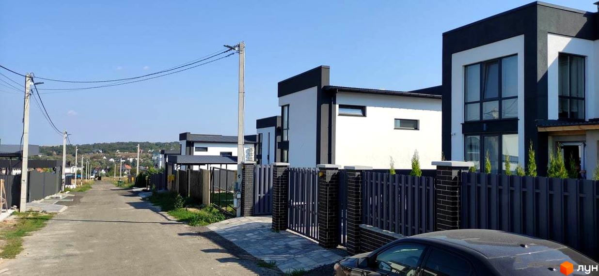 Котеджне містечко Tivoli: фасади будинків з білою та чорною обробкою, огороджена територія з парканом та бруківкою.