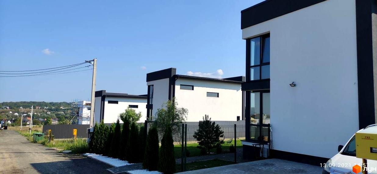 Котеджне містечко Tivoli: білі будинки з чорними елементами та великими вікнами, огороджена територія з туями та парканом.