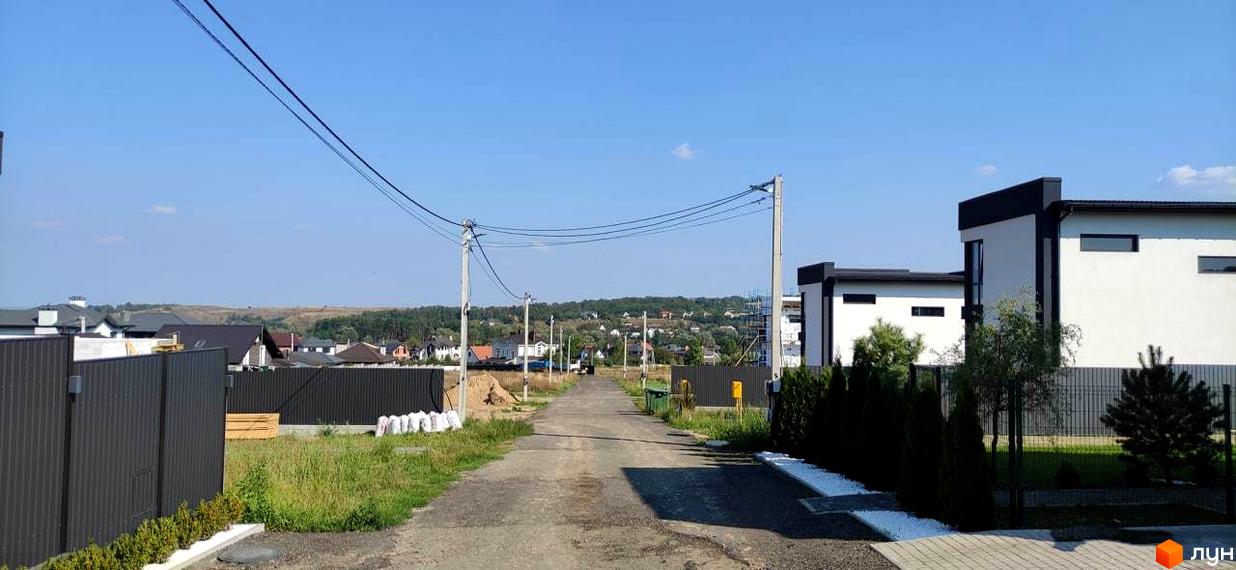 Котеджне містечко KМ Tivoli: білі будинки з чорними елементами та огороджена територія з деревами.