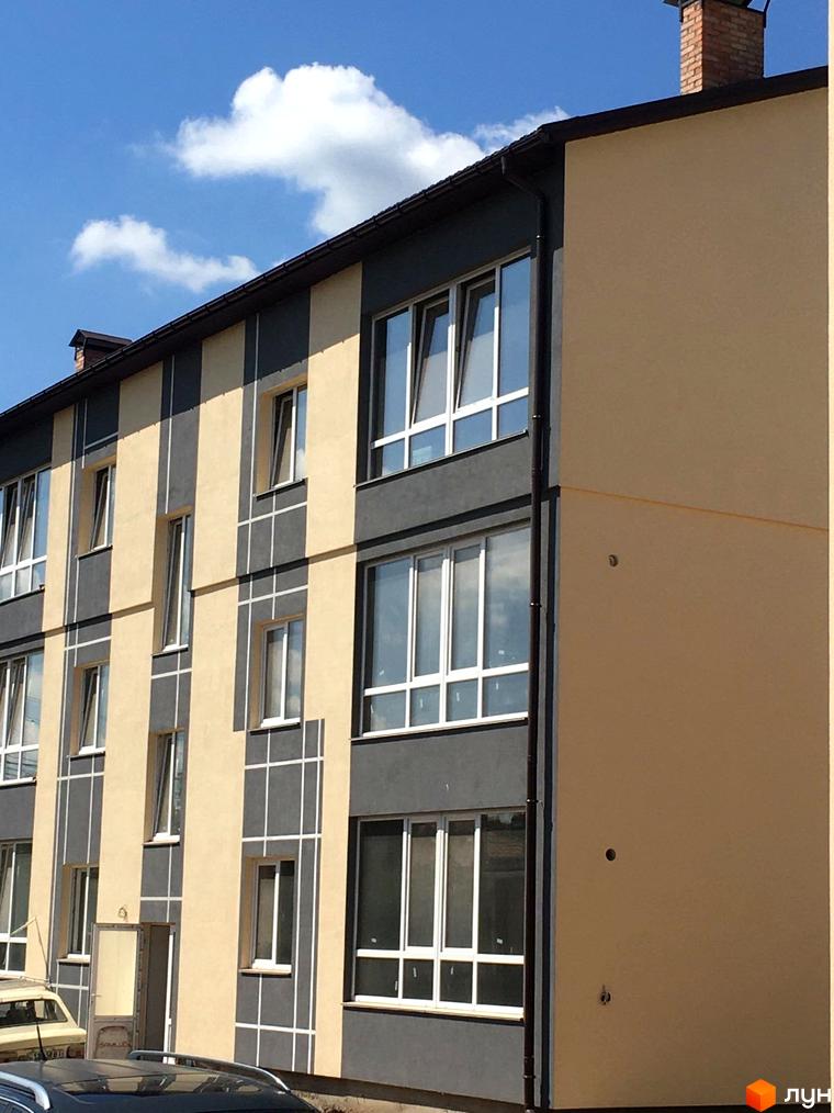 Фасад житлового комплексу ЖК Flat city у сіро-бежевих тонах з великими вікнами. Будинок має чіткі геометричні форми та вертикальні елементи.