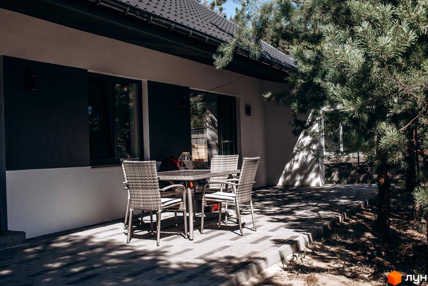 Зовнішній вигляд будинку з терасою та плетеними меблями. Тераса з видом на зелену зону біля котеджного містечка КМ Chaletville.