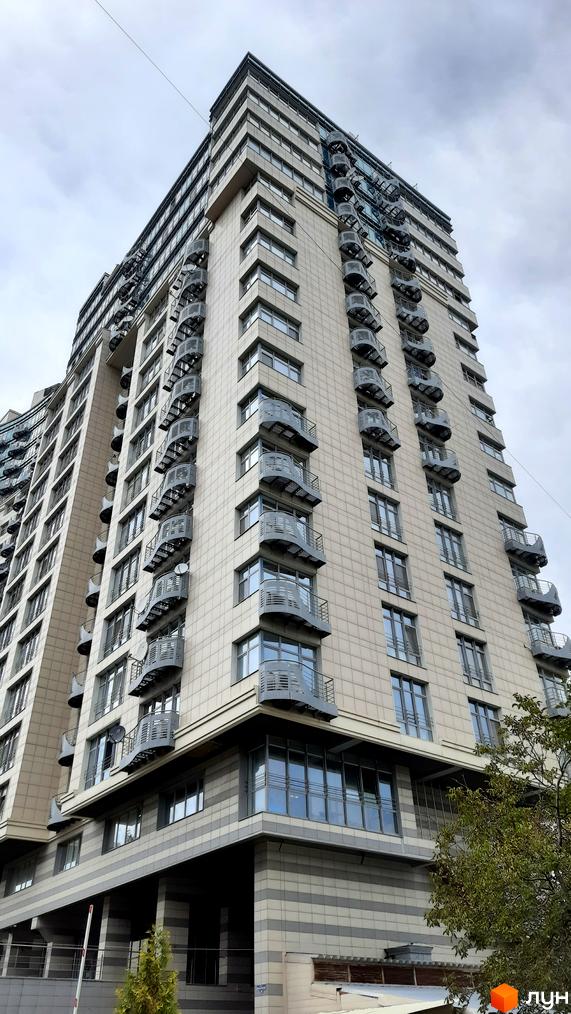 Зовнішній вигляд новобудови ЖК Парус з численними балконами та панорамними вікнами. Будинок має світлу облицювальну плитку та сірі декоративні елементи.
