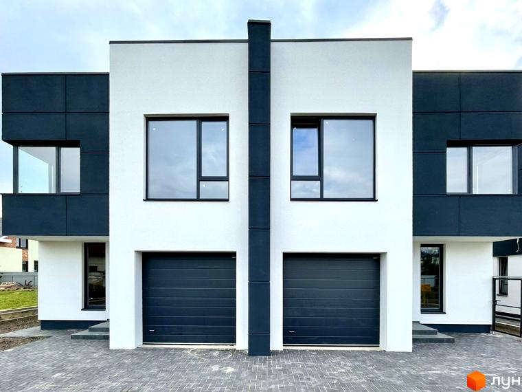 Двоповерховий житловий будинок на вул. Райдужна з біло-сірим фасадом, великими вікнами та гаражними воротами. Перед будинком вимощена територія.