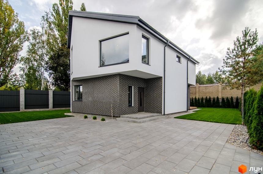 Котеджне містечко КМ Friends Club: двоповерховий будинок з білою та цегляною обробкою, великим вікном, вимощеним подвір'ям та зеленим газоном.