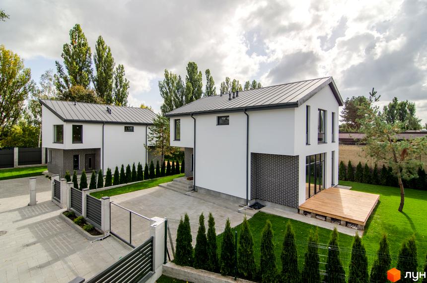 Котеджне містечко КМ Friends Club: білі двоповерхові будинки з темним дахом та цегляним цоколем, огороджена територія з газоном та деревами.