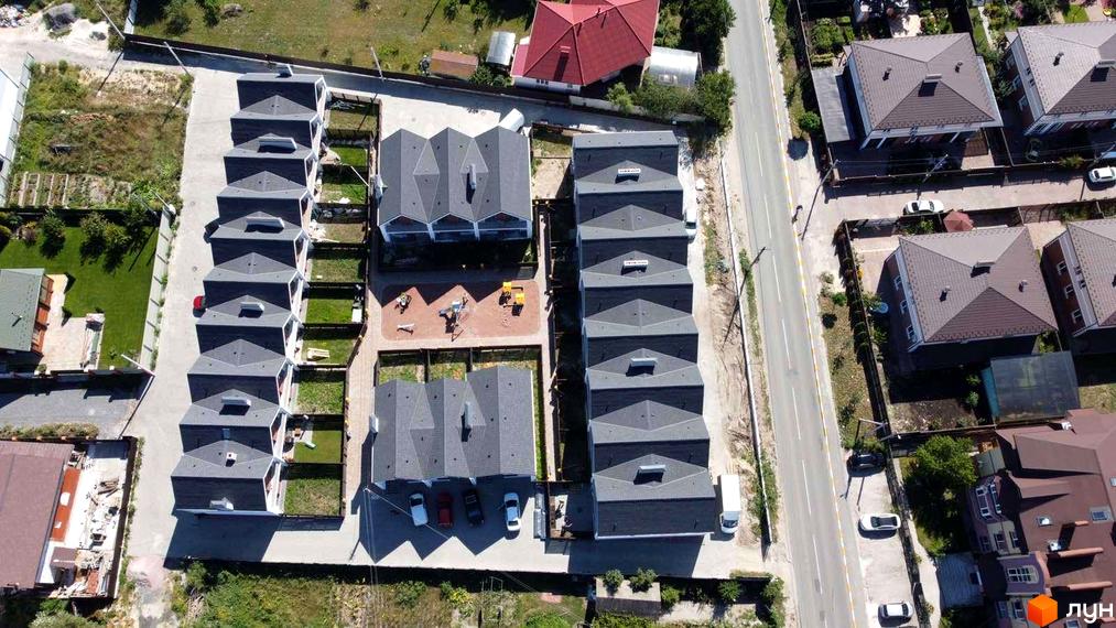 Таунхауси Scandi House з сірими дахами та білими фасадами, розташовані на зеленій ділянці з доглянутою територією та дитячим майданчиком.