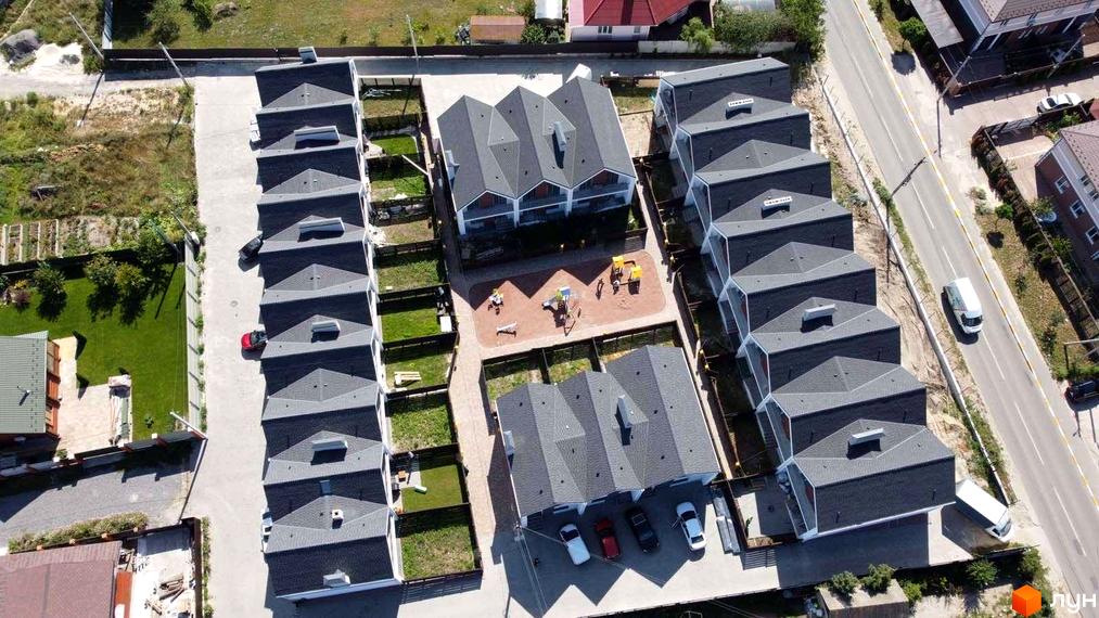 Зовнішній вигляд таунхаусів Scandi House з сірими дахами та білими фасадами, поруч дитячий майданчик та зелені ділянки.