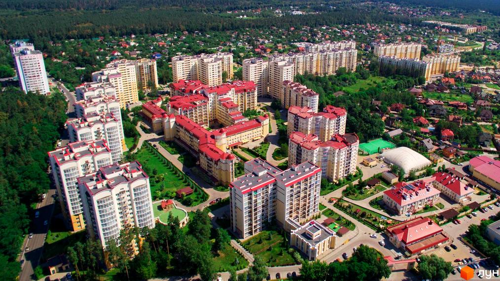 Аерофото Житлового комплексу Чайка: багатоповерхові будинки світлих відтінків з червоними дахами, оточені зеленими насадженнями та інфраструктурою.