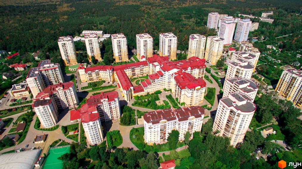 Багатоповерхові будинки Житлового комплексу Чайка з білими фасадами та червоними дахами, розташовані серед зелених насаджень та доріжок.