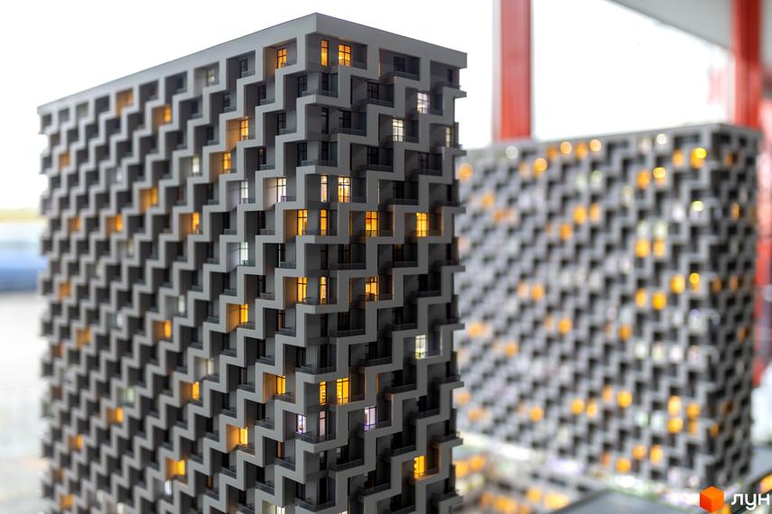 Макет багатоповерхового будинку житлового комплексу BOSTON Creative House. Фасад має рельєфний візерунок із зигзагів, вікна освітлені.