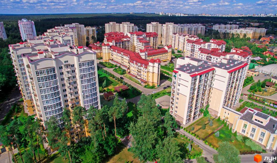 Житловий комплекс Чайка з багатоповерховими будинками світлих відтінків та червоними дахами. Територія має зелені насадження та доріжки.