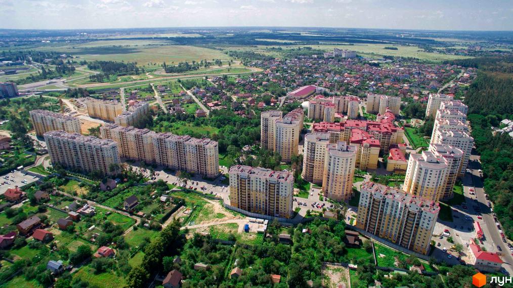 Аерофотографія житлового комплексу Чайка: багатоповерхові будинки світлих тонів з червоними дахами, розташовані серед зелених зон та доріг.