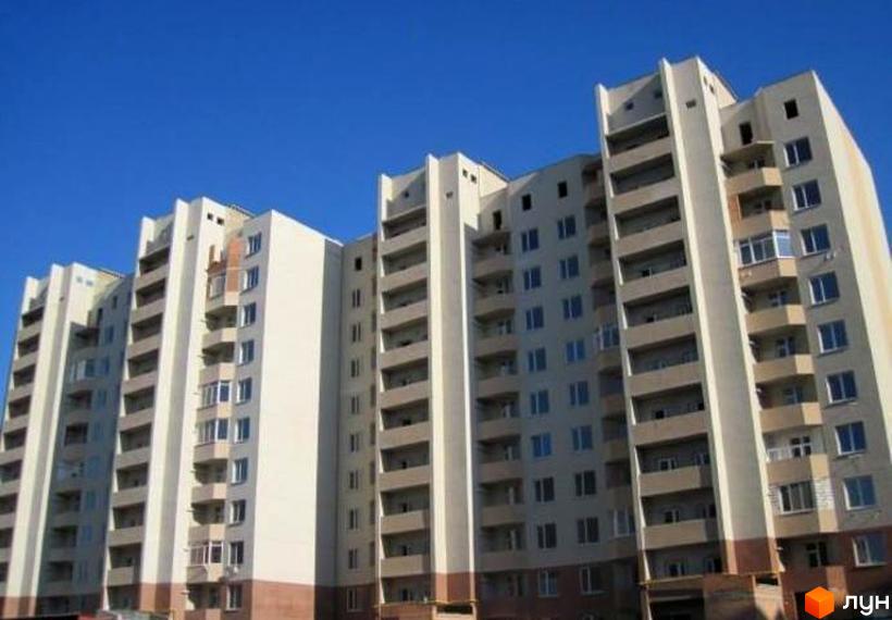 Висотна новобудова ЖК Ідеал-2 з великою кількістю балконів та вікон. Насичений колір неба підкреслює архітектуру будівлі.