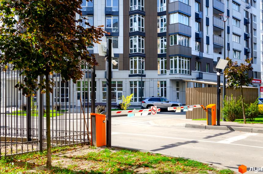 Житловий комплекс Святобор: фасади будівель з великими вікнами та балконами, огороджена територія з автоматичним шлагбаумом та зеленими насадженнями.