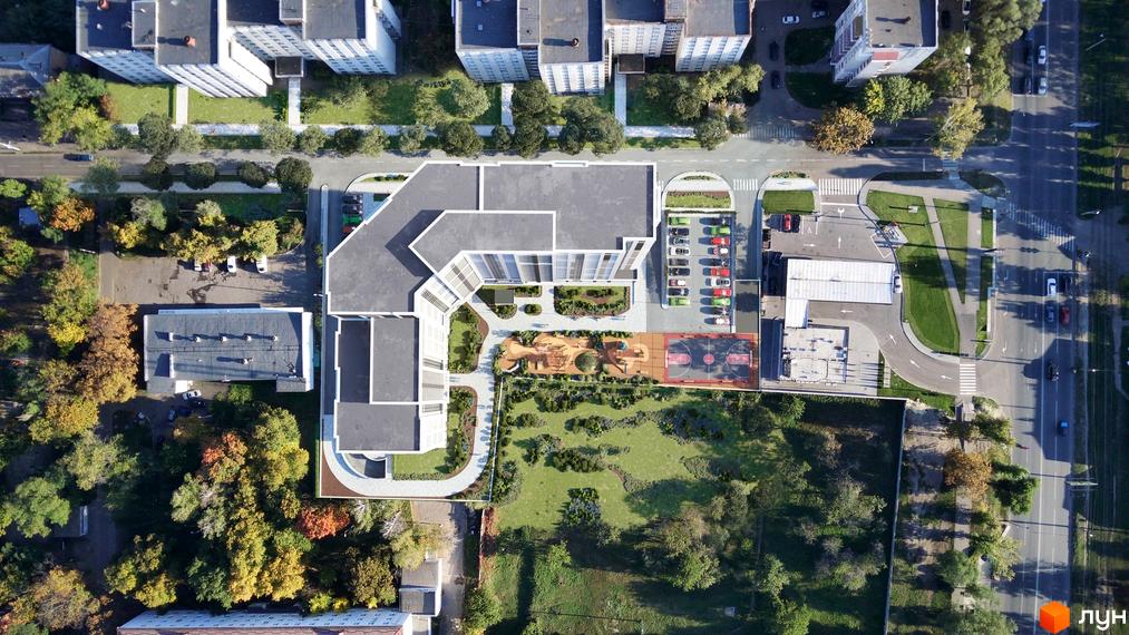 Аерофотозйомка житлового комплексу Liberty Gardens з багатоповерховими будинками, внутрішнім двором з дитячим майданчиком та спортивними зонами, а також прилеглою територією з деревами та дорогою.