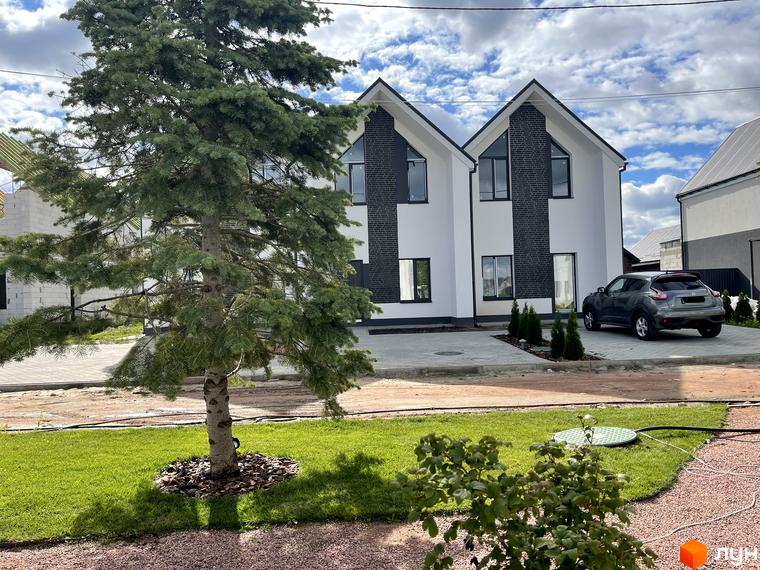 Зовнішній вигляд двох будинків котеджного містечка Щаслива Вулиця з прибудинковою територією та деревами. Новобудова з білим фасадом та темними акцентами.
