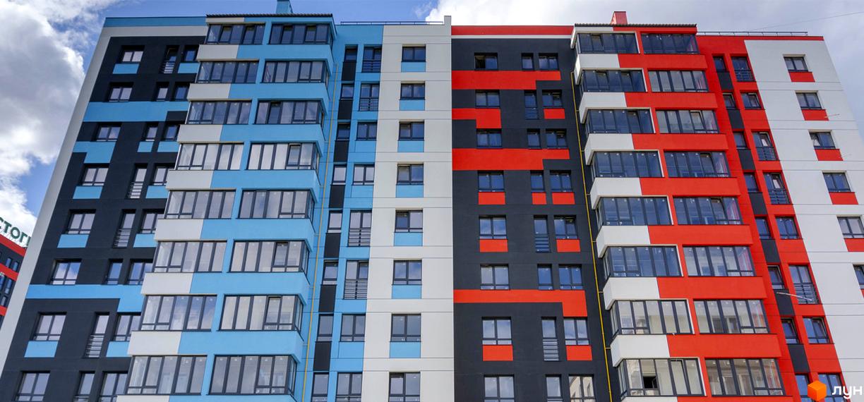 Зовнішній вигляд новобудови ЖК Bridge Town з яскравим фасадом у синьо-біло-чорних та червоно-біло-чорних кольорах. Будинок має багато вікон та балконів.