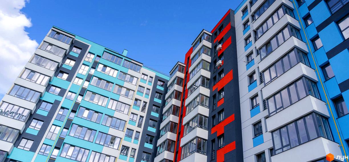 Житловий комплекс Bridge Town – це багатоповерхові будинки з яскравим фасадом у блакитних та червоних кольорах. Вікна панорамні, балкони виступають.