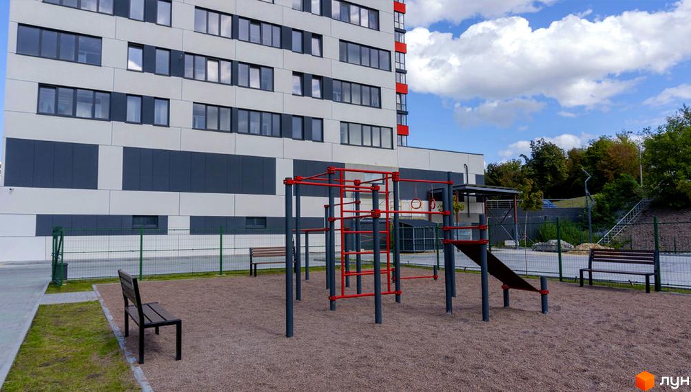 Житловий комплекс Bridge Tower з сучасною архітектурою та облаштованим дитячим майданчиком. Зовнішній вигляд будівлі та прибудинкова територія.