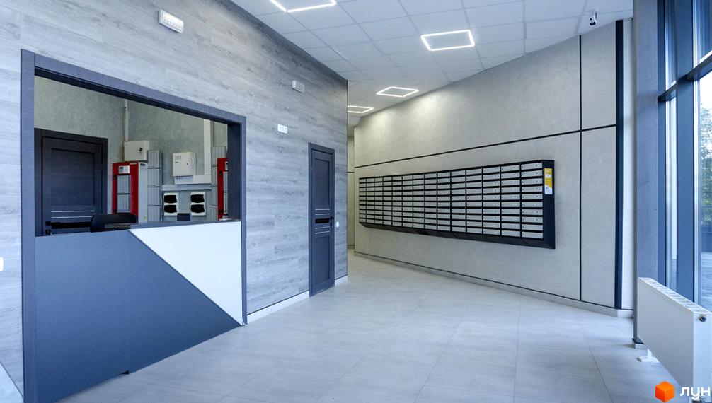 Вхідна група житлового комплексу Bridge Tower з рецепцією та поштовими скриньками. Сучасний дизайн холу з великими вікнами та радіатором.