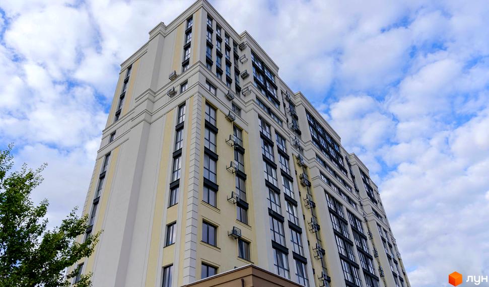 Висотна новобудова ЖК Prestige Apartments з великою кількістю вікон на тлі блакитного неба з хмарами. Фасад будівлі виконаний у світлих тонах.