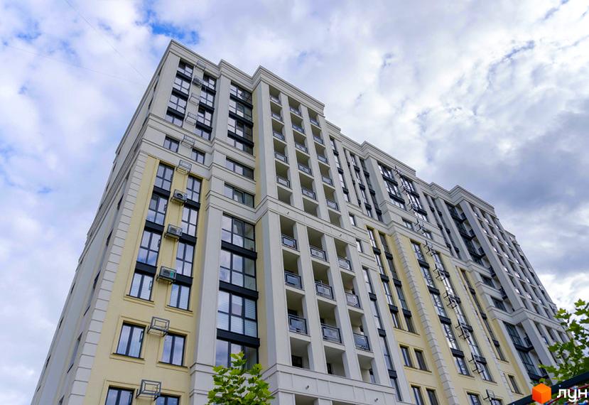 Висотна будівля ЖК Prestige Apartments з великою кількістю вікон та балконів. Фасад будинку виконаний у світлих тонах, на фоні блакитного неба з хмарами.