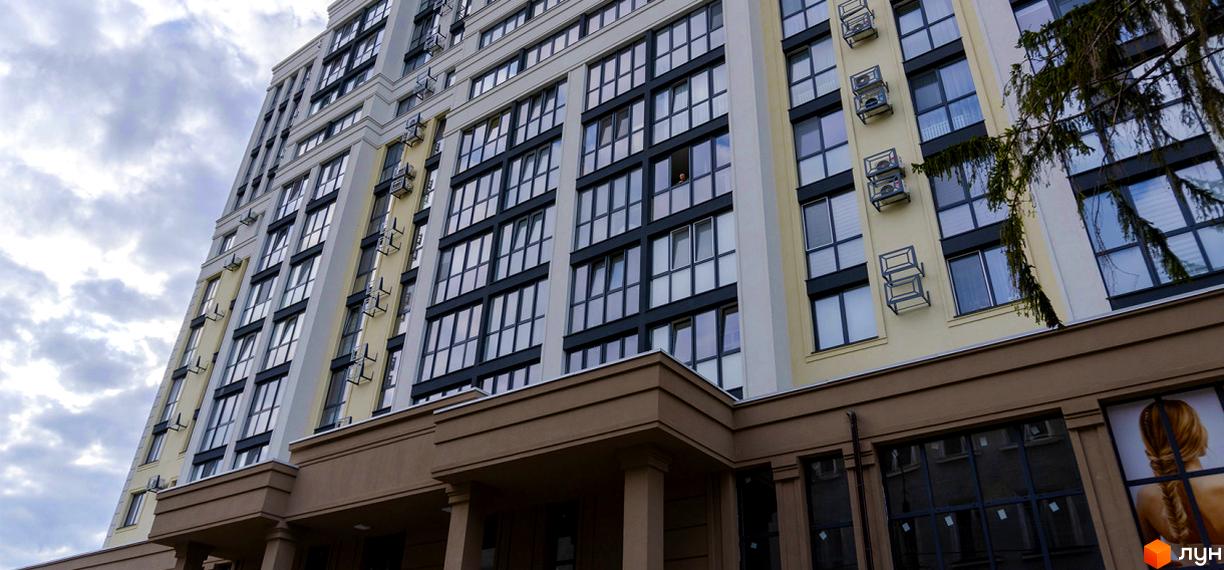 Висотна будівля ЖК Prestige Apartments з великою кількістю вікон. Фасад будівлі виконаний у світлих тонах з темними віконними рамами.