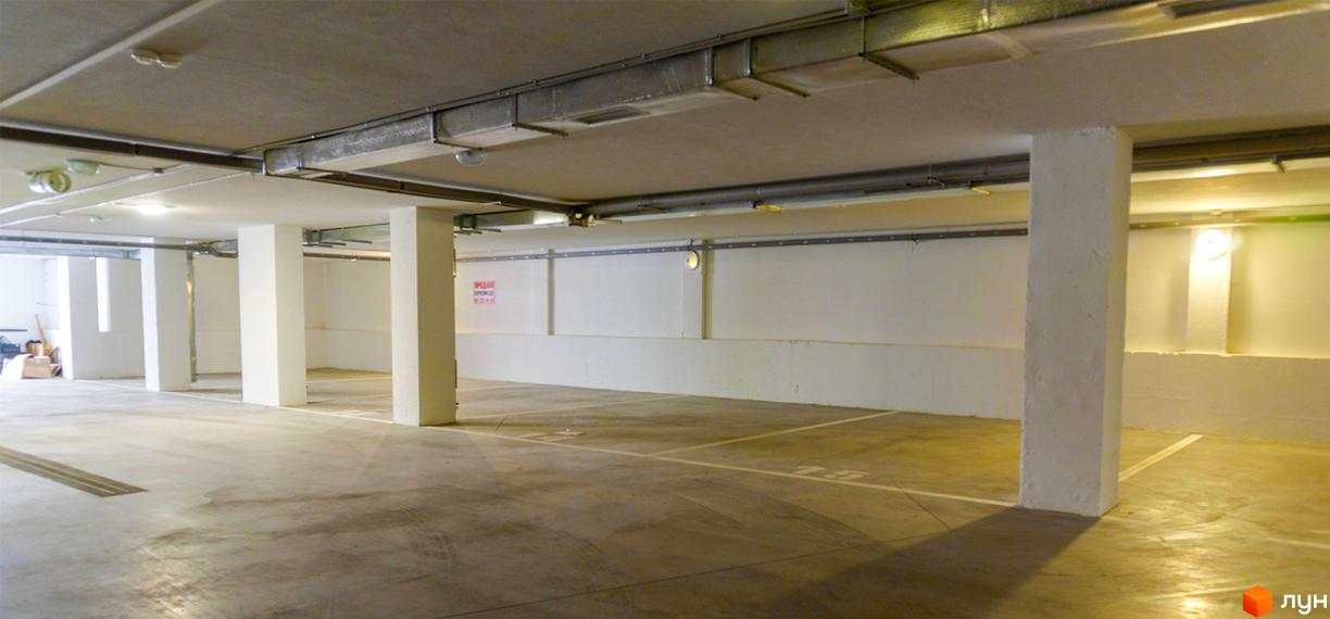 Підземний паркінг в ЖК Prestige Apartments. Просторий паркінг з бетонною підлогою та білими колонами.