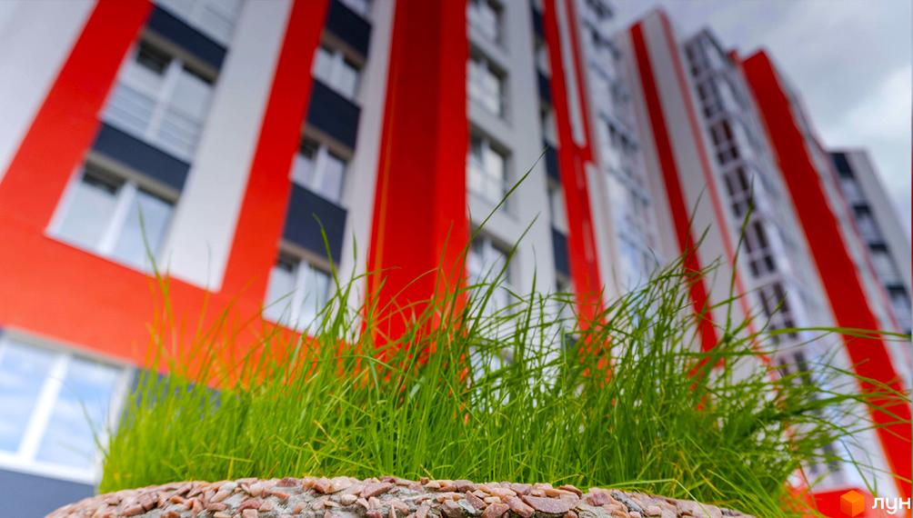 Житловий комплекс Корольова з яскравим фасадом у червоно-білих тонах та зеленою галявиною перед будинком.